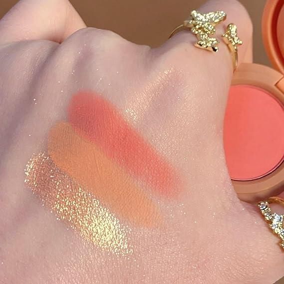 Swatches of fupei2-e5 3 in 1 face blusher showing peach, coral, and highlighter shades on hand