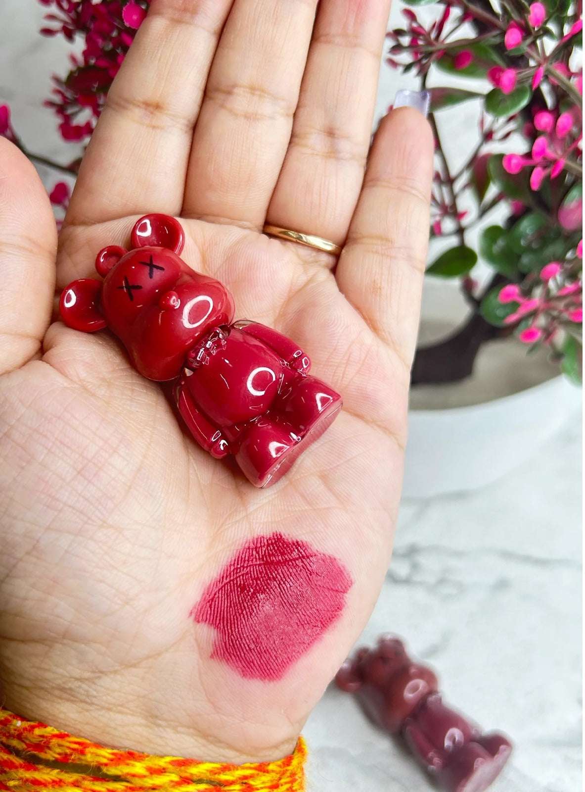 19203 long lasting lip tint set with a textured bear-shaped applicator and vibrant color swatch on the hand